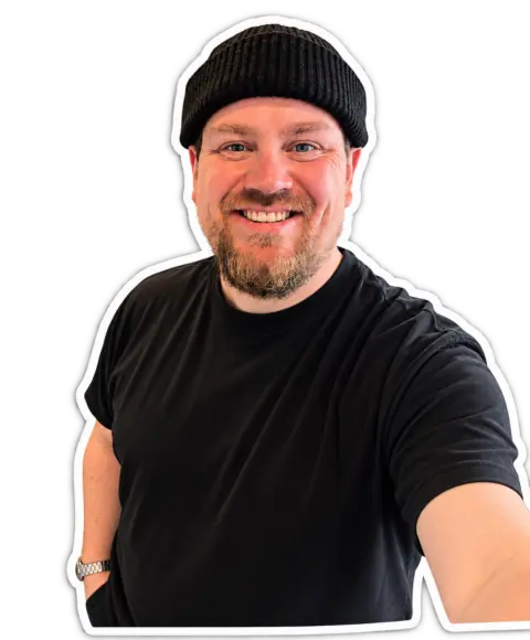 René Kirk i sort hue og sort T-shirt, smilende